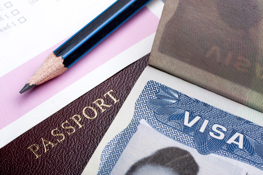 Image: a closeup of a passport and h-1b visa